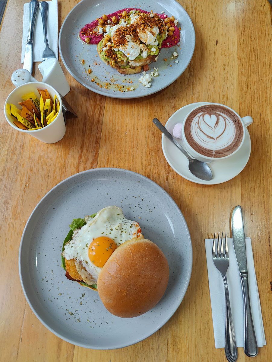 A table topped with plates of food and a cup of coffee.