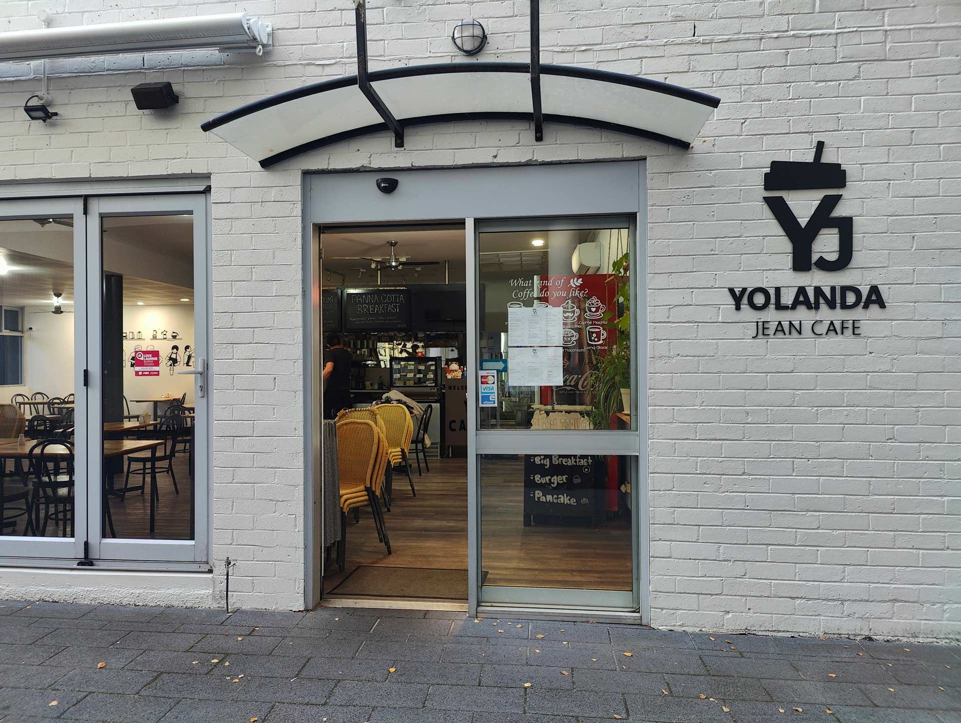 A white brick building with a sign that says yolanda jean cafe