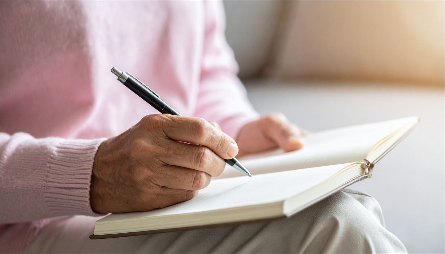 A close-up of a person in a pink sweater writing in a notebook, showing how to use REMS technology
