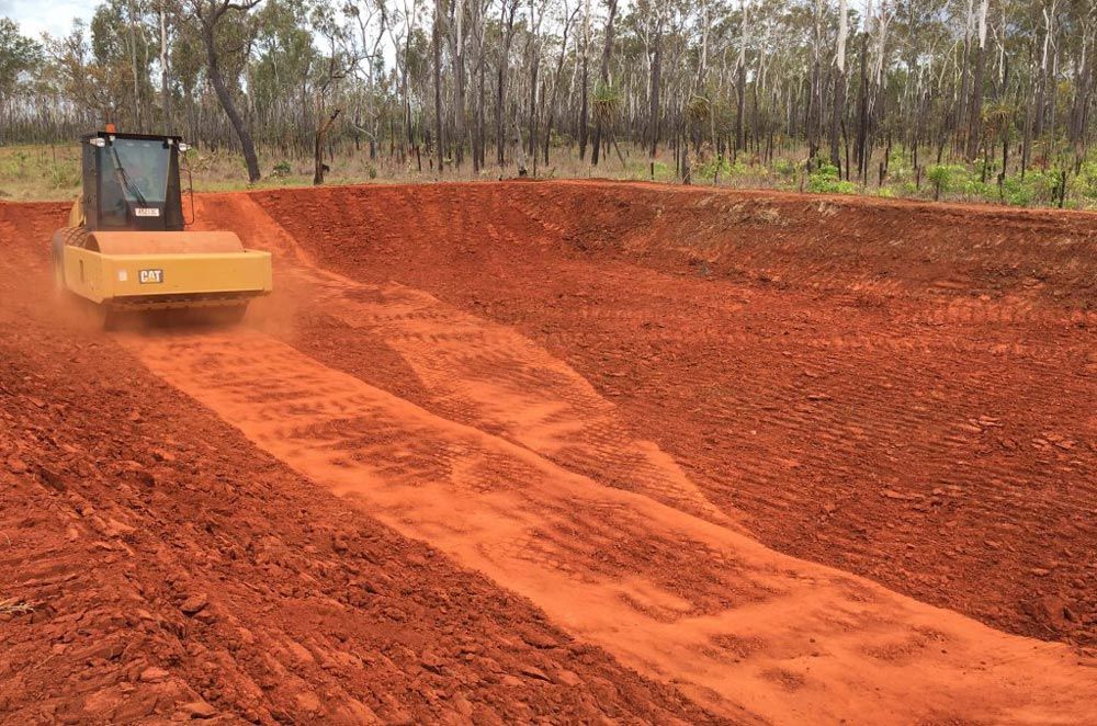 A Bulldozer Is Driving Down A Dirt Road For Site Preparation — Coleman's Contracting & Earthmoving In Humpty Doo, NT
