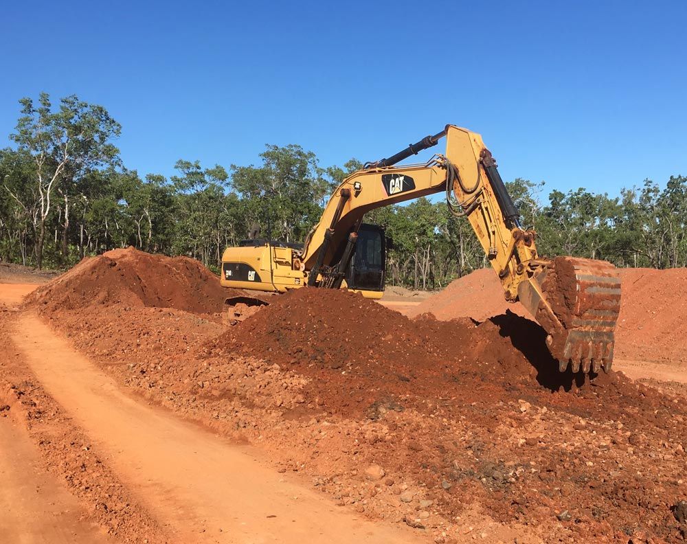 Yellow Excavator Is Collecting Dirt Pile On The Field — Coleman's Contracting & Earthmoving In Humpty Doo, NT