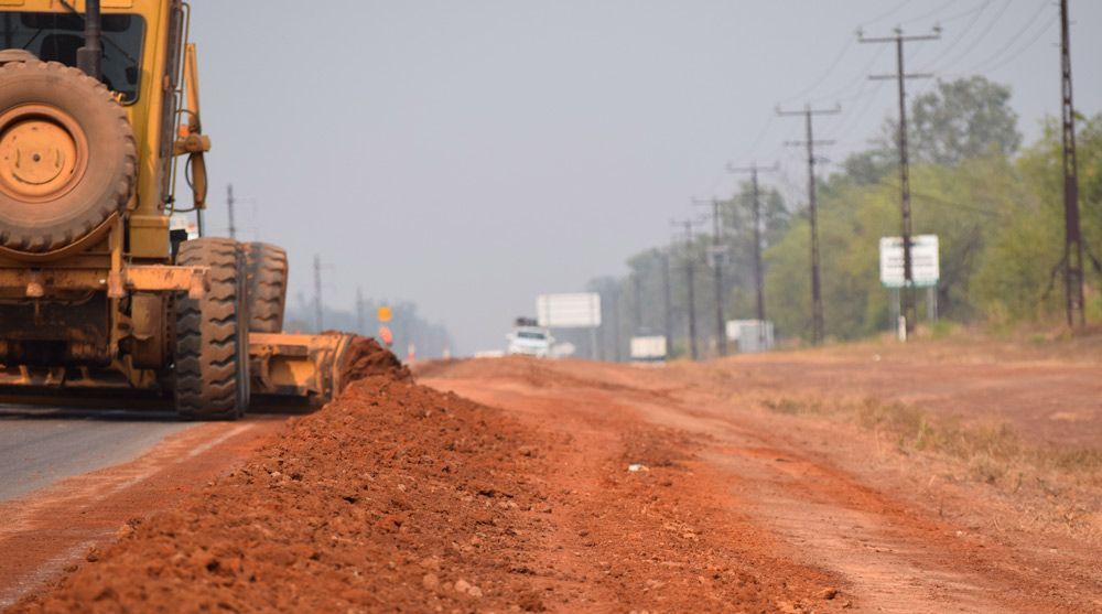 An Earthmoving Bulldozer Is Driving Down A Dirt Road — Coleman's Contracting & Earthmoving In Humpty Doo, NT