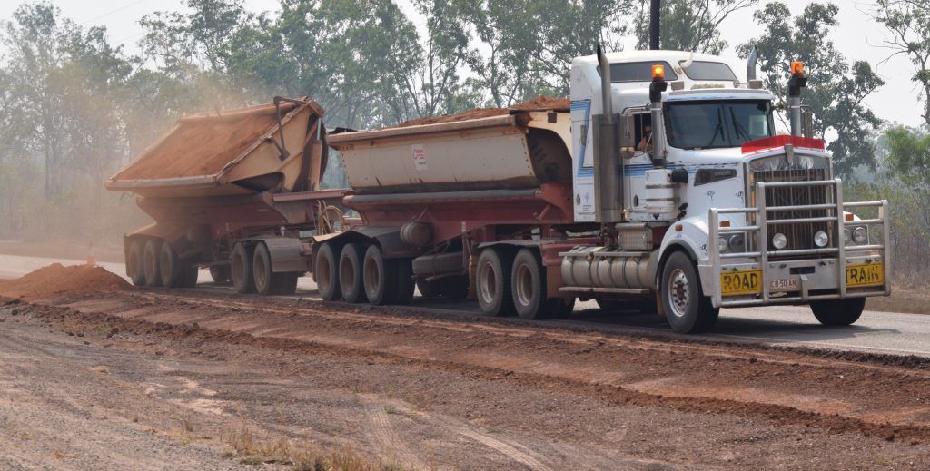 A White Semi Truck Is Unloading The Dirt Besides A Dirt Road — Coleman's Contracting & Earthmoving In Humpty Doo, NT