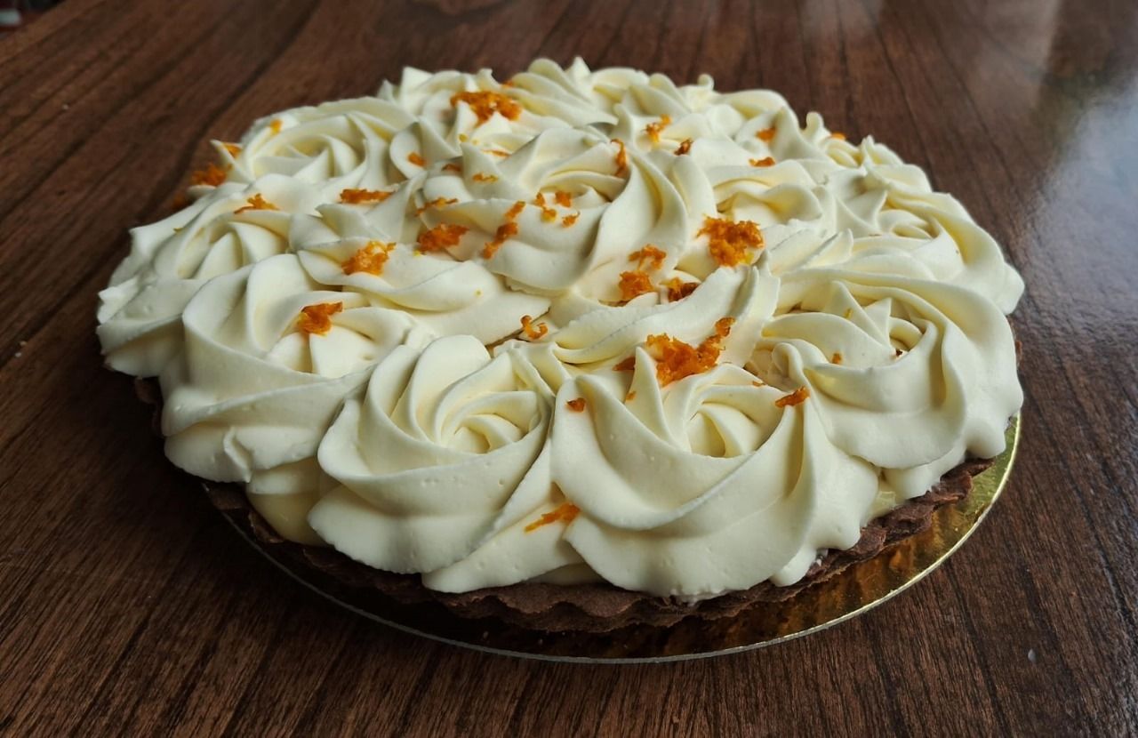 Un pastel con crema batida encima está sobre una mesa de madera.