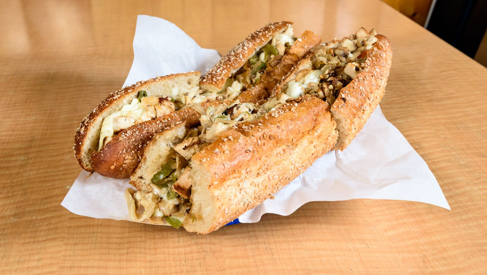 Two toasted sandwiches on a paper-lined tray on a wooden table