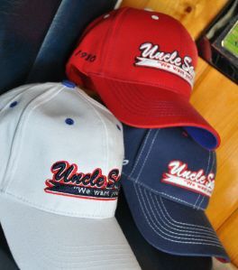 Three baseball caps in red, white, and navy blue, each embroidered with 