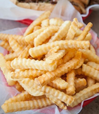 A basket filled with golden-brown crinkle-cut fries lined with white paper.