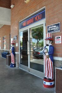 Two Uncle Sam statues stand outside a brick building entrance with a 