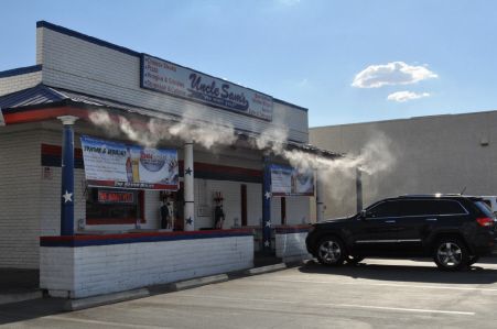 Uncle Sam's restaurant front, painted in red, white, and blue, with misting fans spraying under the building's overhang.