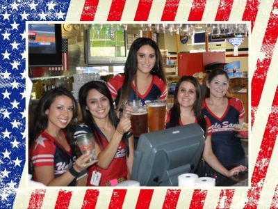 Four employees in red, white, and blue uniforms work behind a bar, some holding glasses of beer.