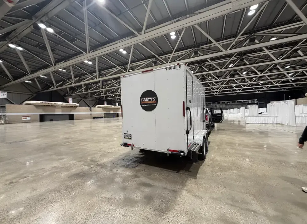 A white trailer parked inside a spacious warehouse, surrounded by industrial shelving and equipment