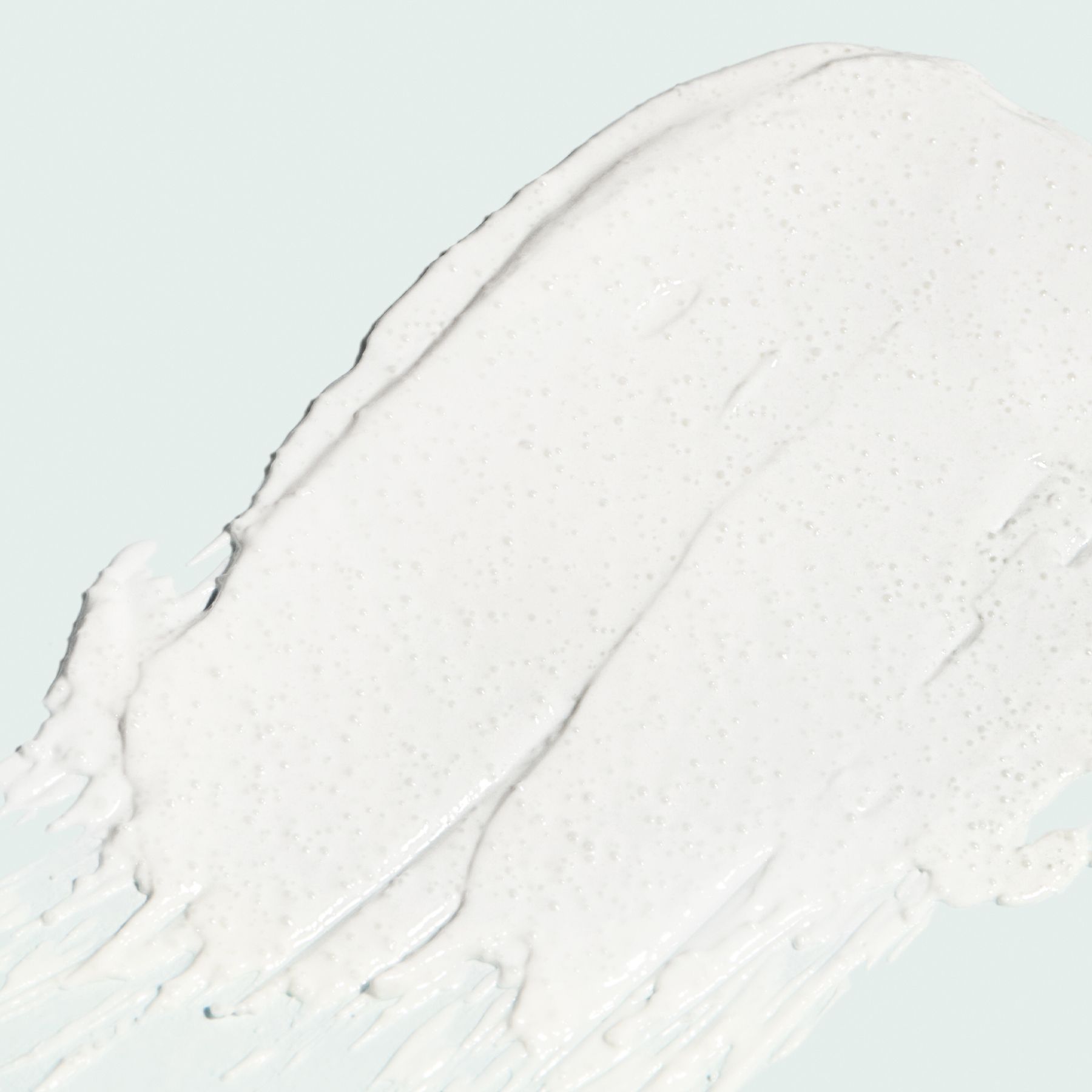 White cosmetic product smear on a light blue background.