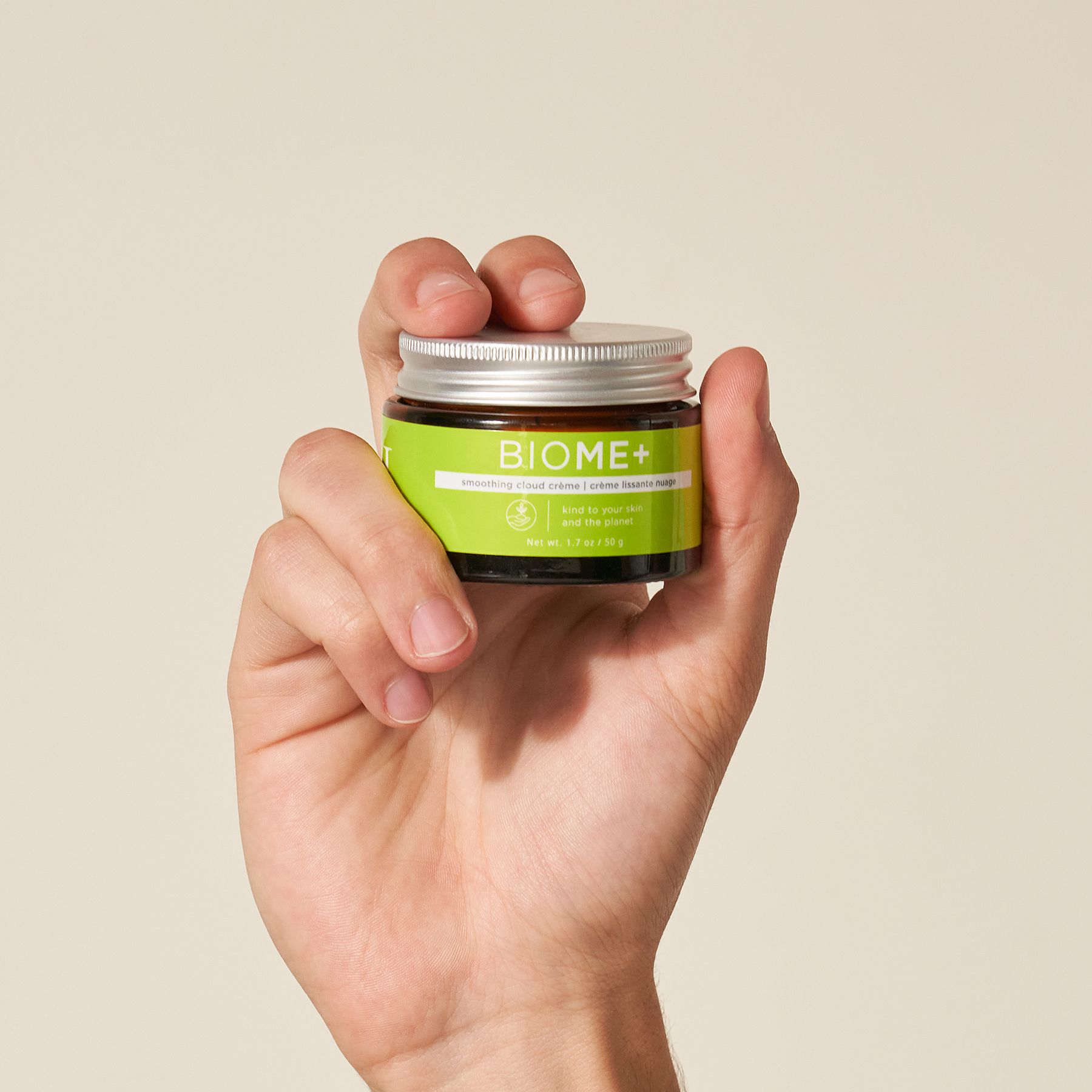 Hand holding a small jar of moisturizer