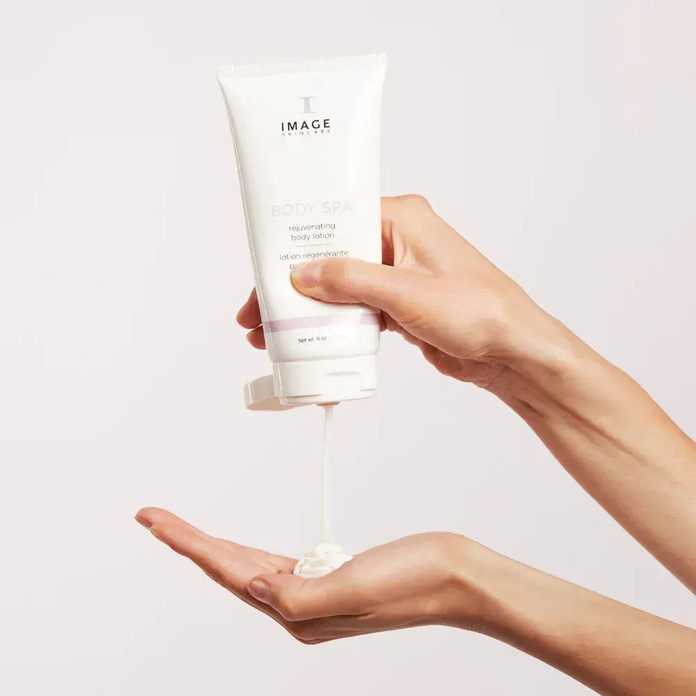 Person squeezing body lotion from a white tube into their hand.