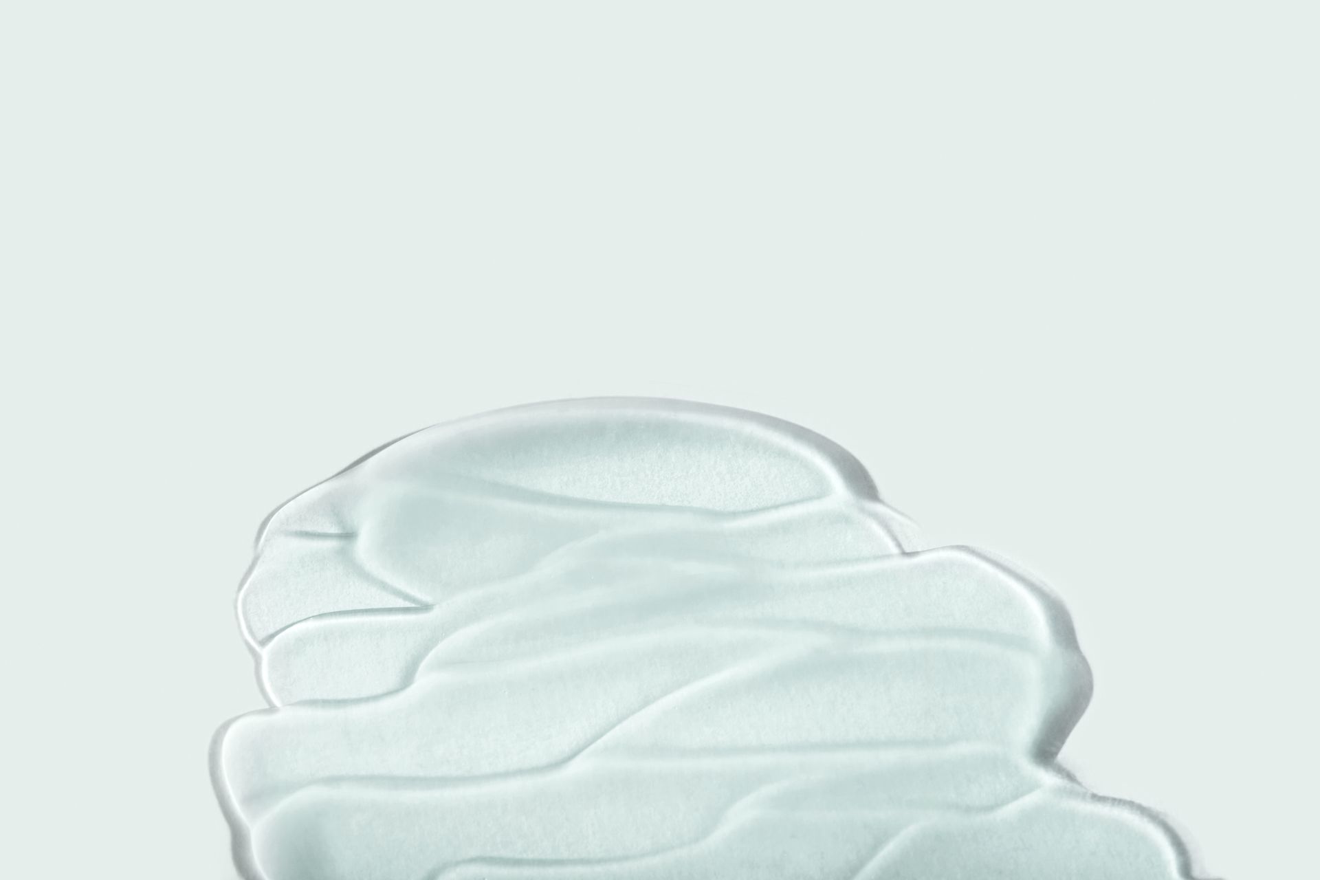 A blob of clear gel with subtle texture, on a light blue-gray background.