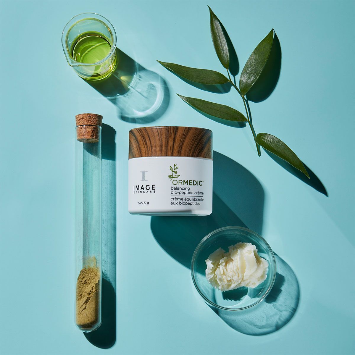 Skincare product with ingredients like leaf, serum, and shea butter on a blue background.