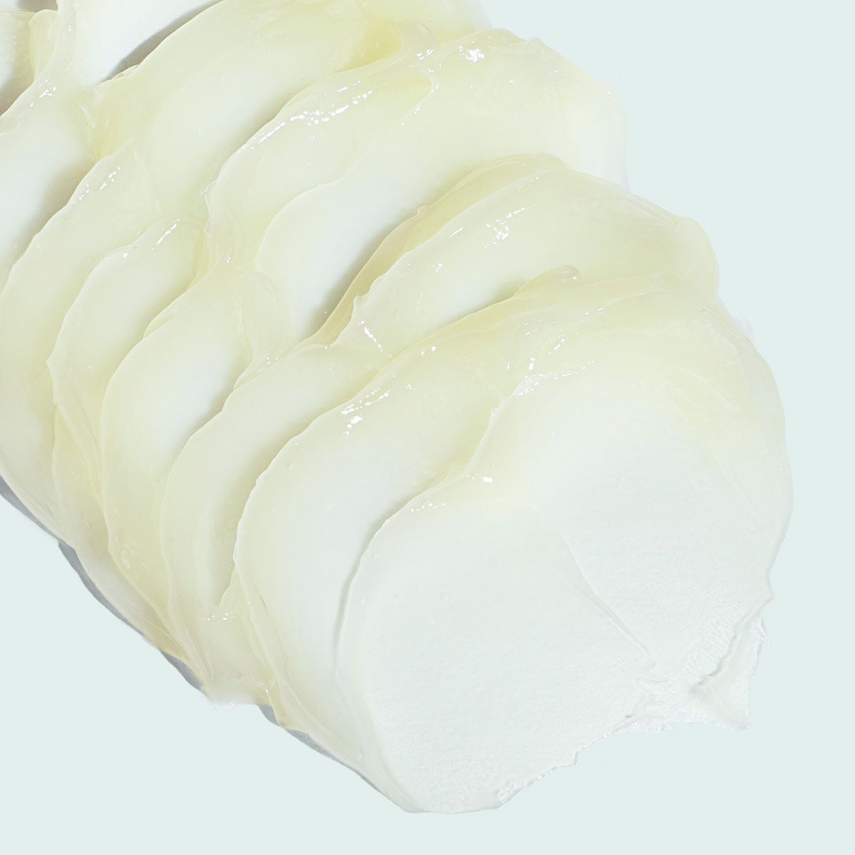 Slices of a thick, off-white cosmetic product spread on a light background.