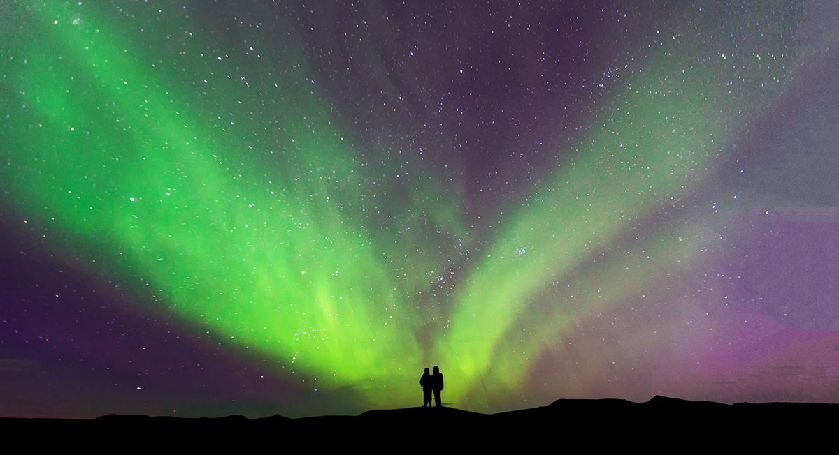 A couple embrace under Finland's aurora borealis.