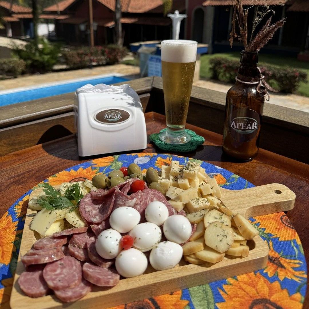Tábua de frios com cerveja e petiscos à beira da piscina.
