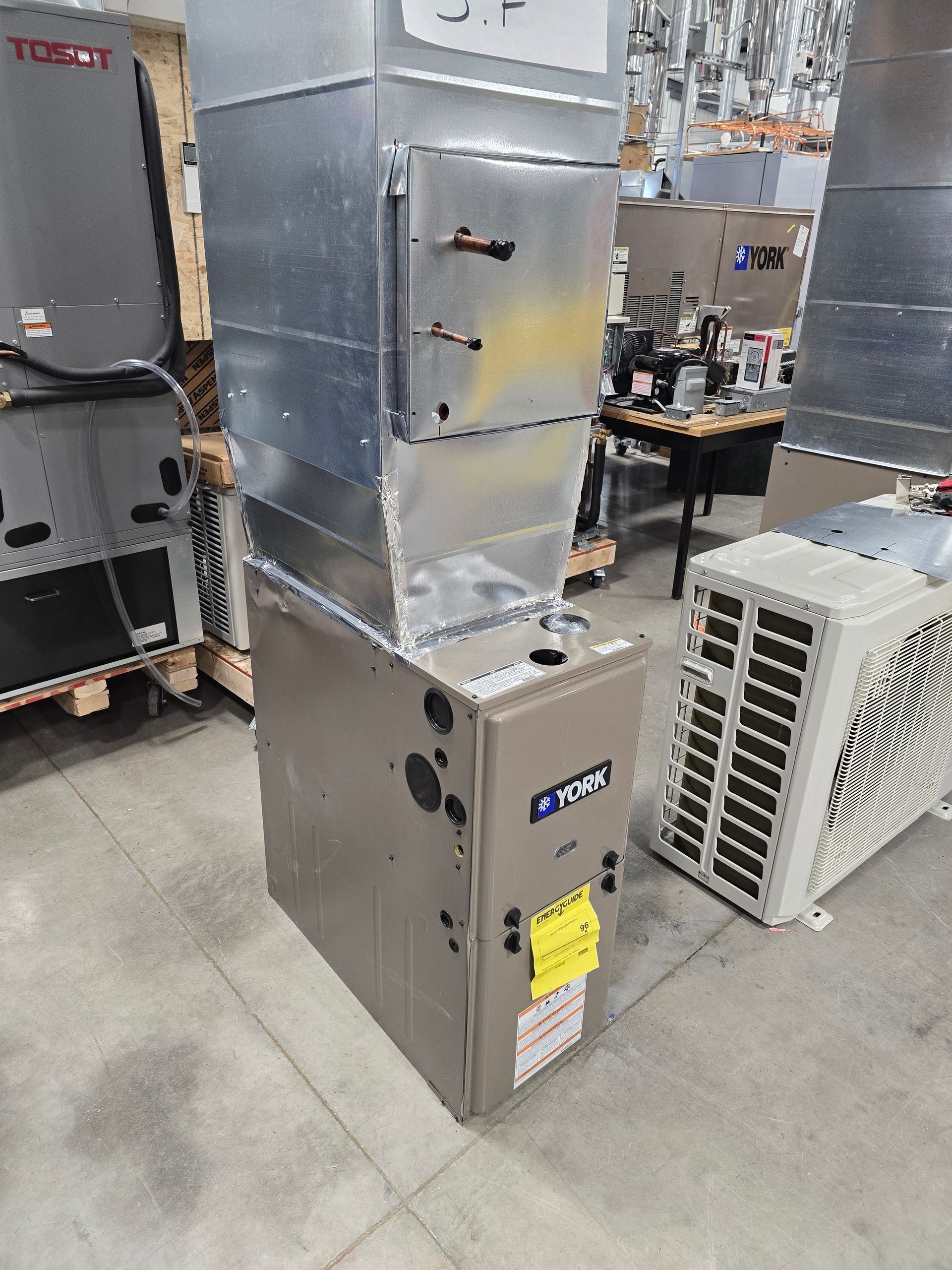 Man in blue coveralls and black gloves operating machinery controls near a garage door.