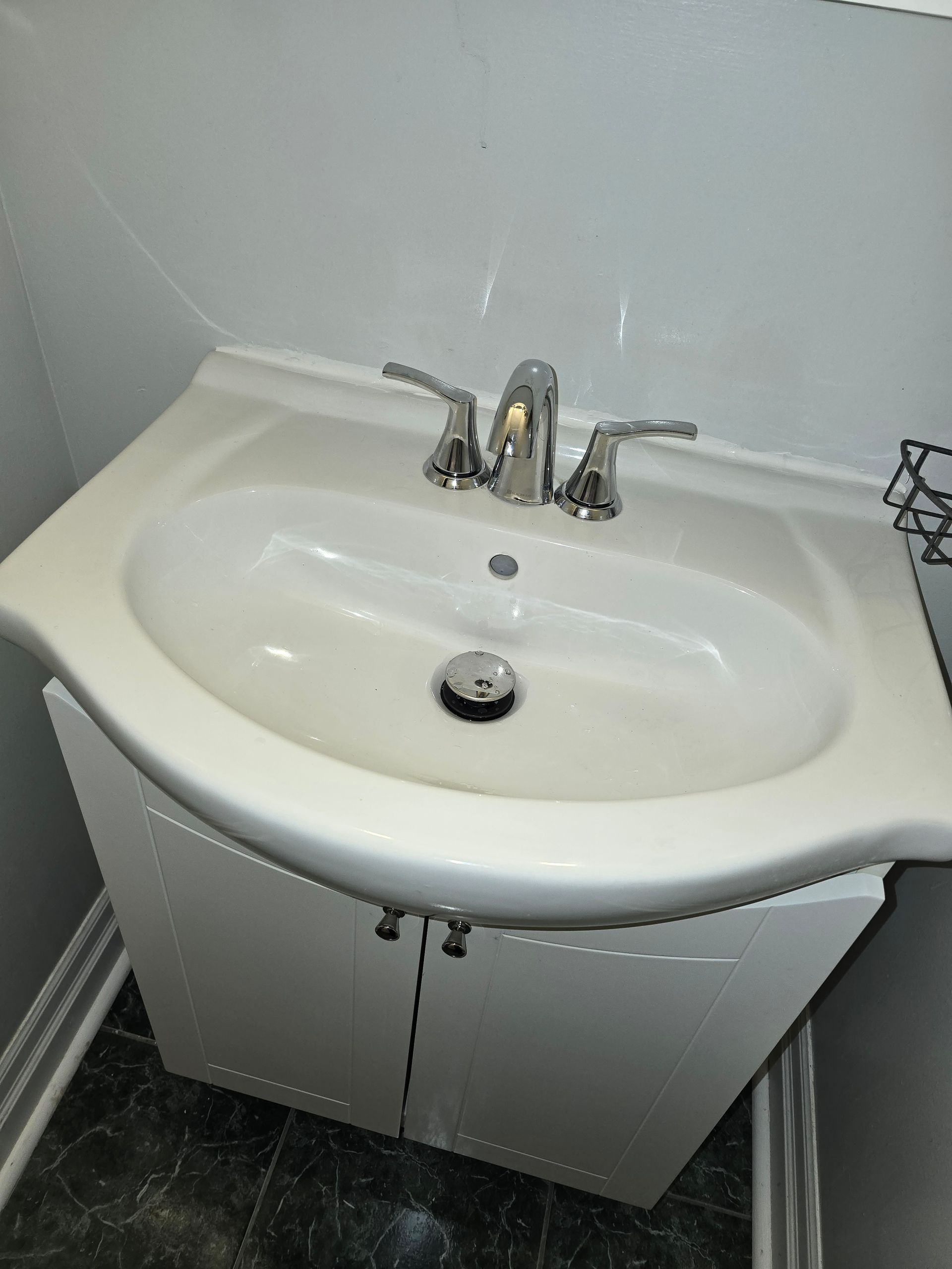 White bathroom sink with chrome faucet and cabinet.
