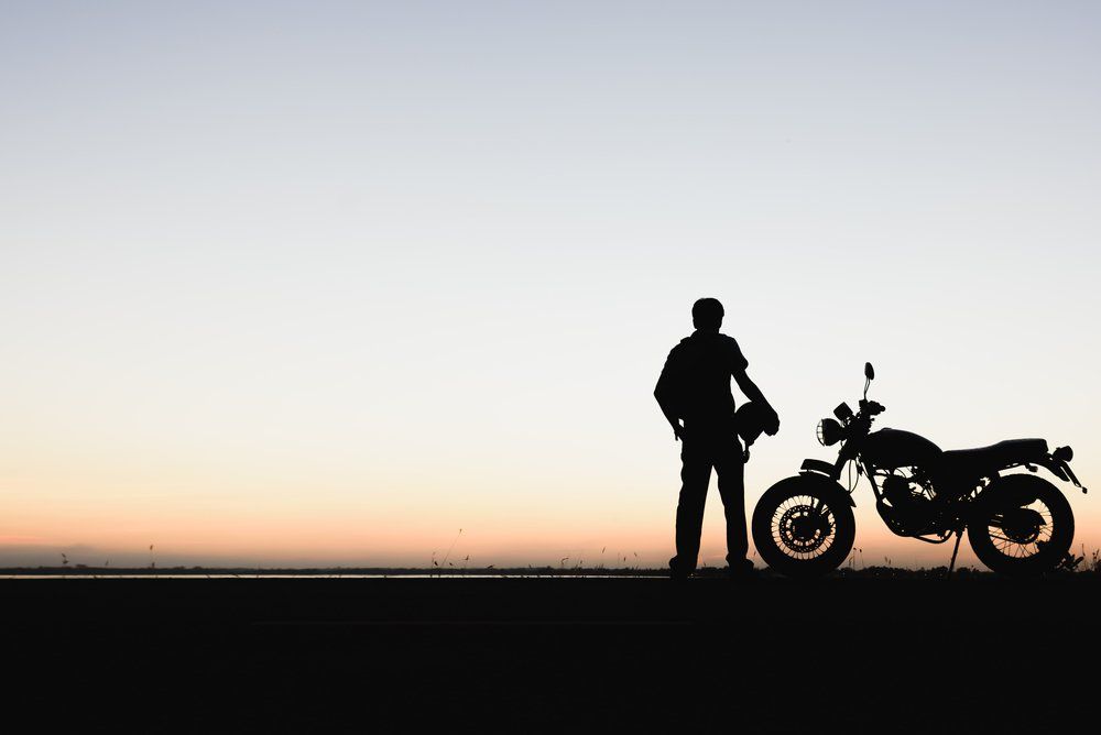 silhouette of man standing by motorcycle