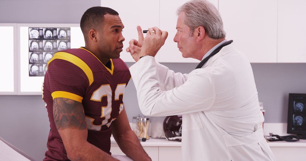 doctor giving a football player a concussion exam 