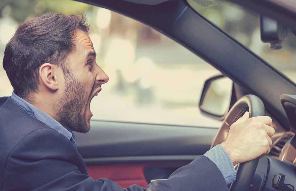 white man sitting in his car yelling because he has road rage 