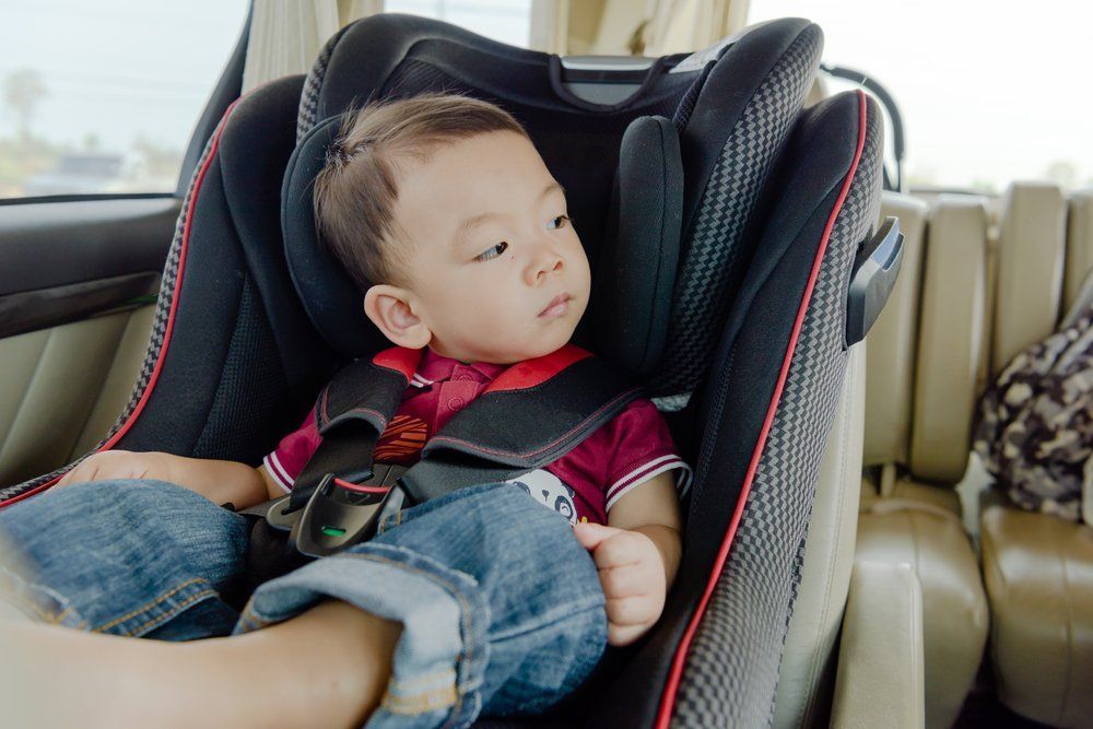 2 year old boy sitting in a booster seat in a car