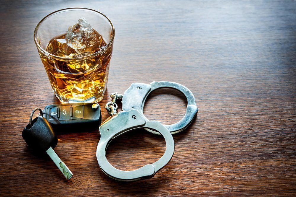 car keys and handcuffs sitting next to a glass of whiskey on a table