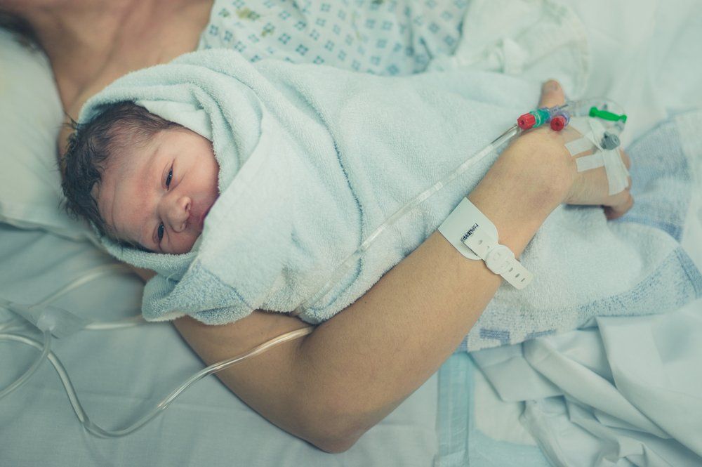 newborn baby being held by mother in delivery room