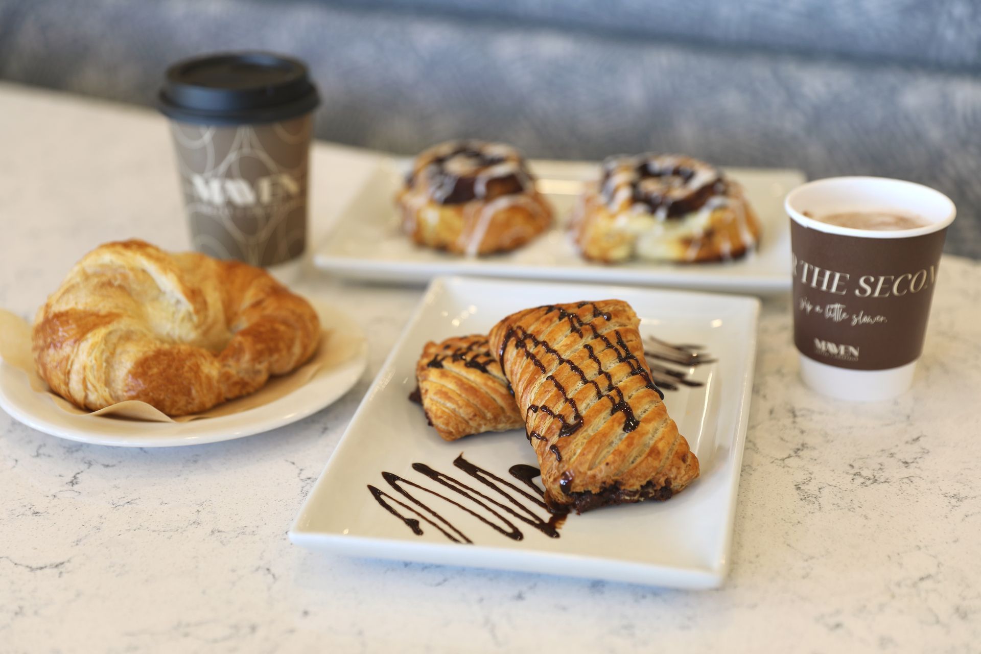 A table topped with plates of pastries and two cups of coffee. 
