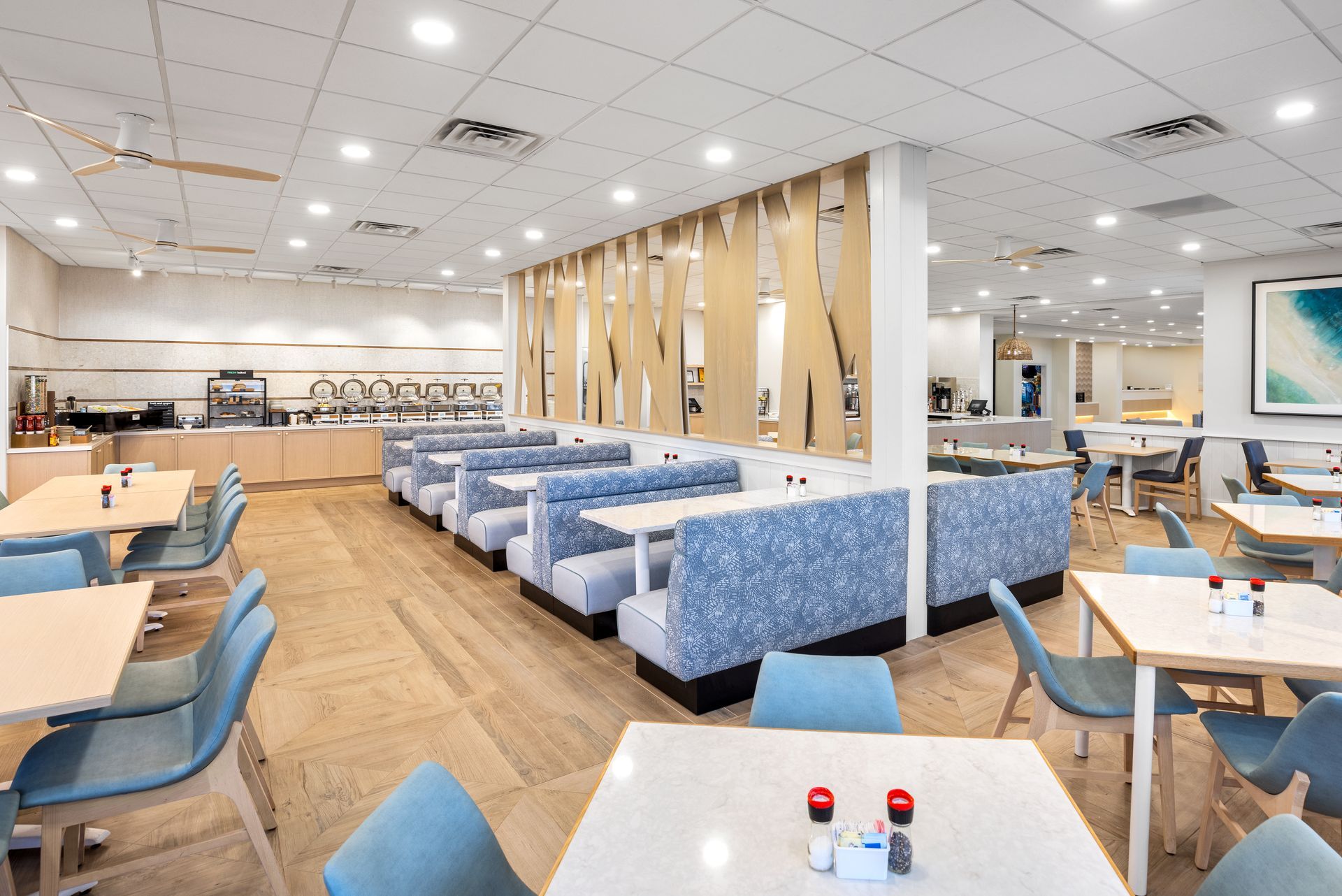 A restaurant with tables and chairs and a breakfast buffet.