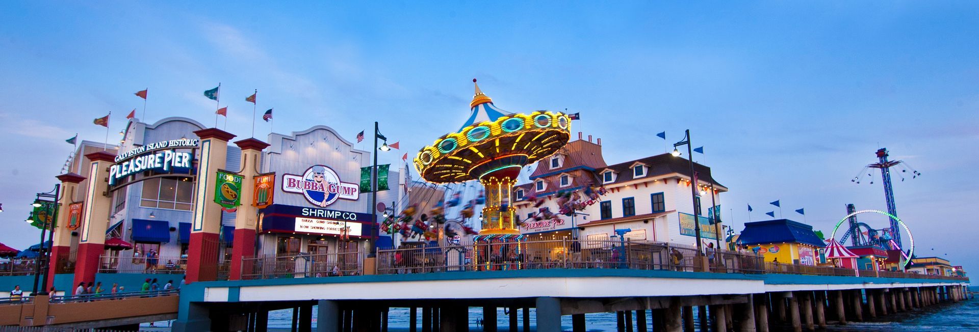 A pier with a carousel and buildings on it.