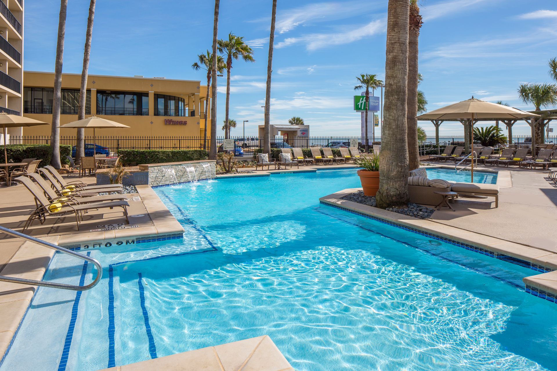 A large swimming pool surrounded by lounge chairs and umbrellas at a resort.