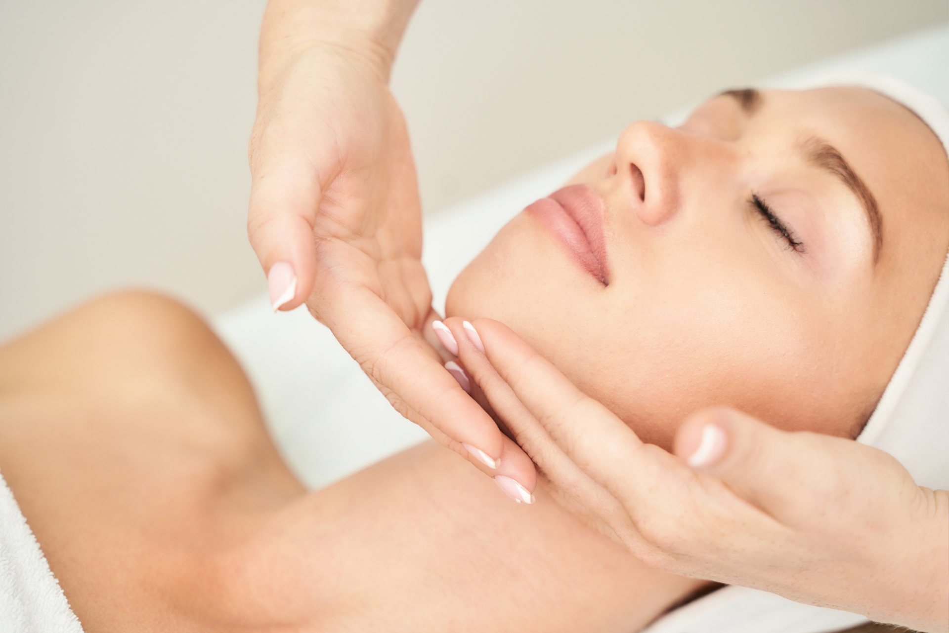 A woman is getting a facial massage at a spa.