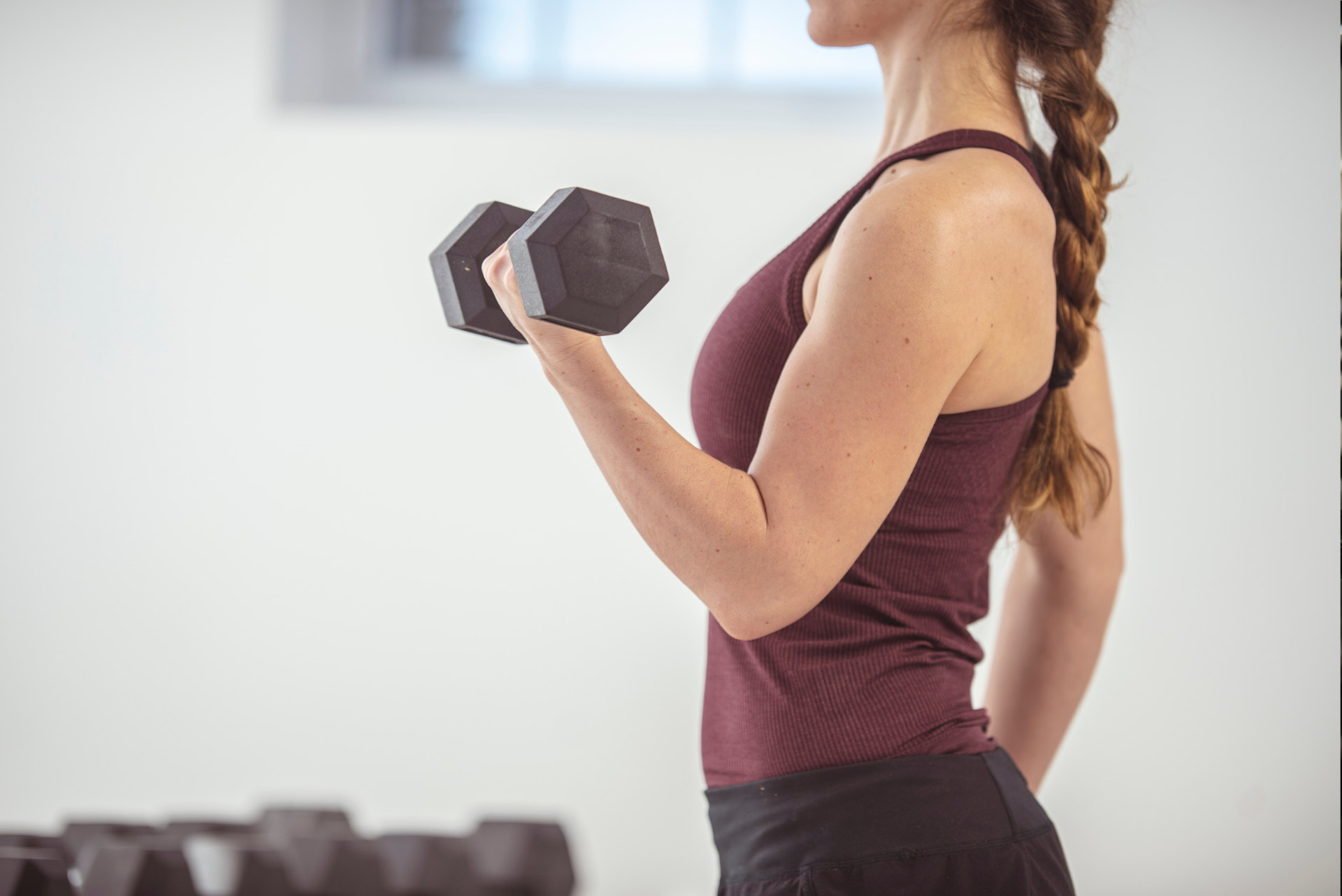 A woman is lifting a dumbbell in a fitness center.