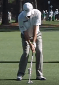 A man is swinging a golf club on a golf course