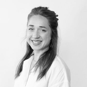 A woman in a white shirt is smiling in a black and white photo.