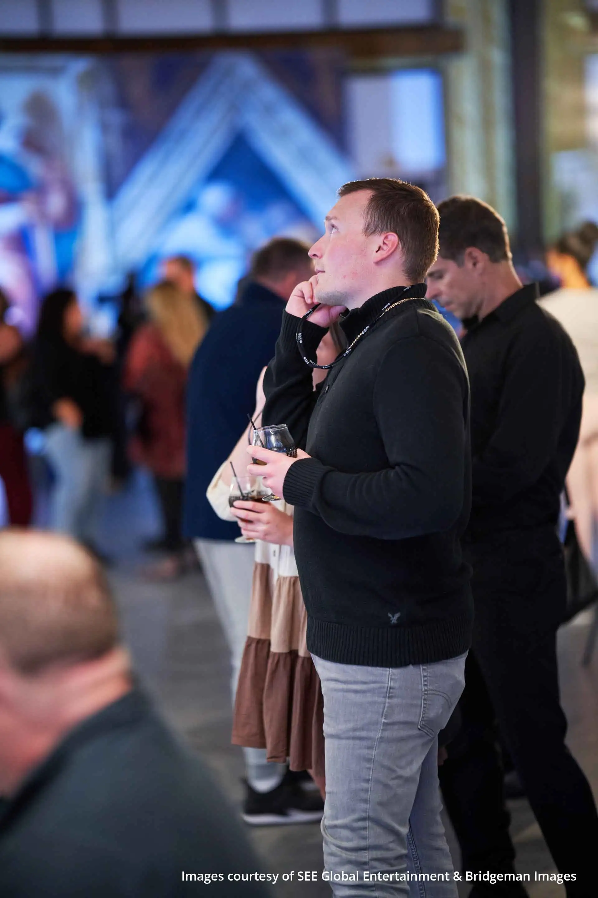 Alors que de nombreux visiteurs déambulent à travers l’exposition sur la chapelle Sixtine, une personne écoute un audioguide.