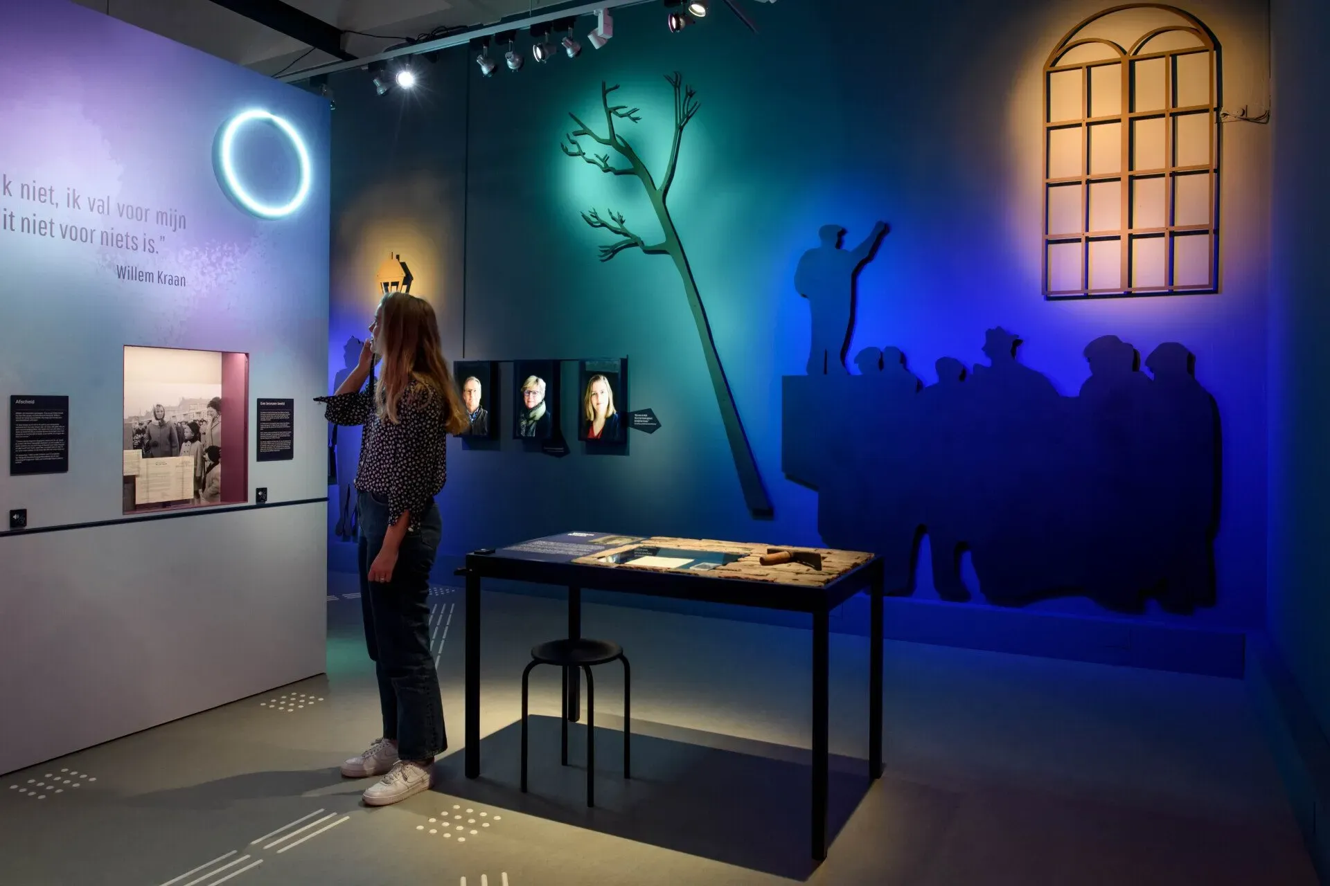 A person listens to the Podcatcher audio guide while reading text on the wall at the Resistance Museum.