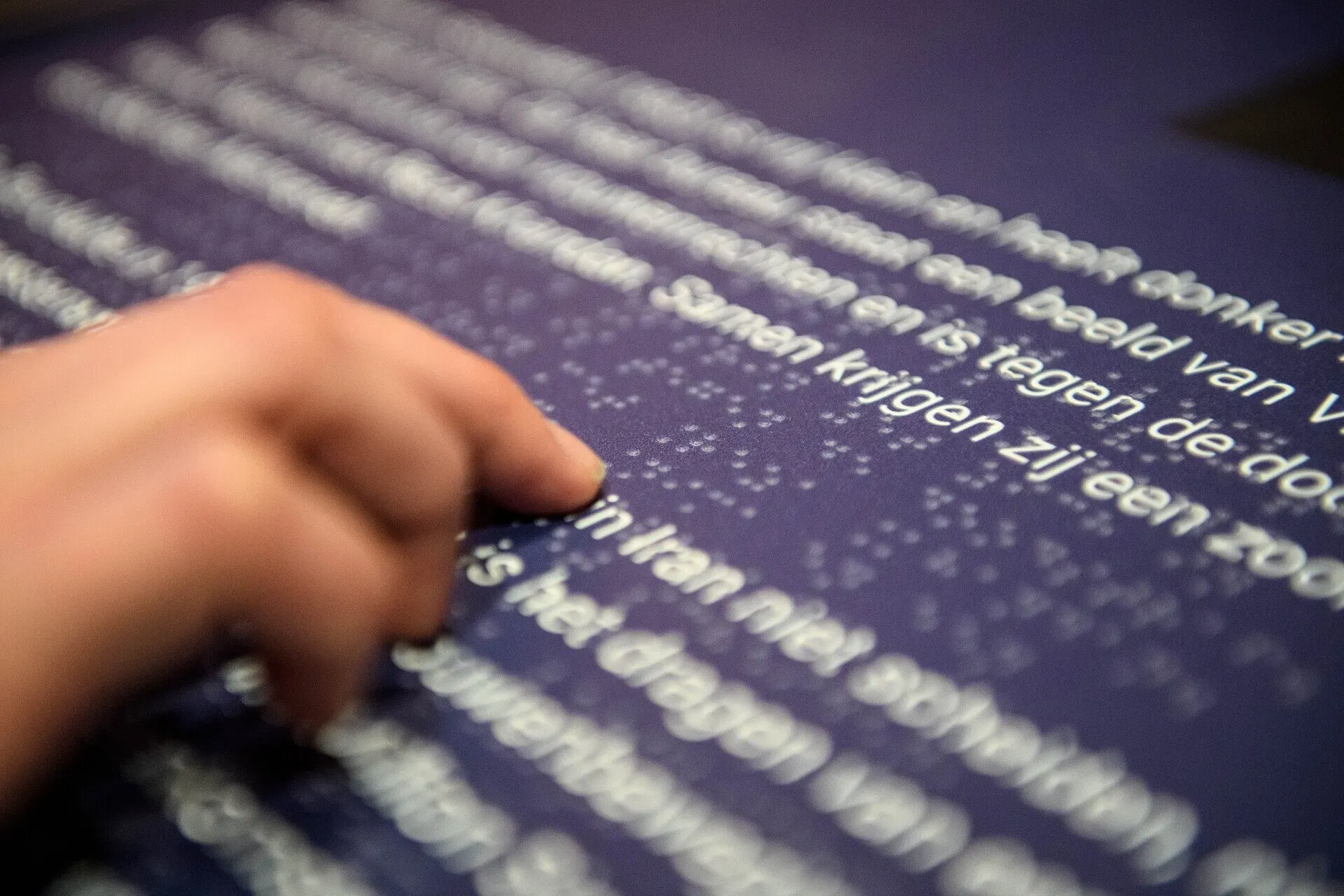 A person is reading an explanation next to the display in braille at the Resistance Museum.