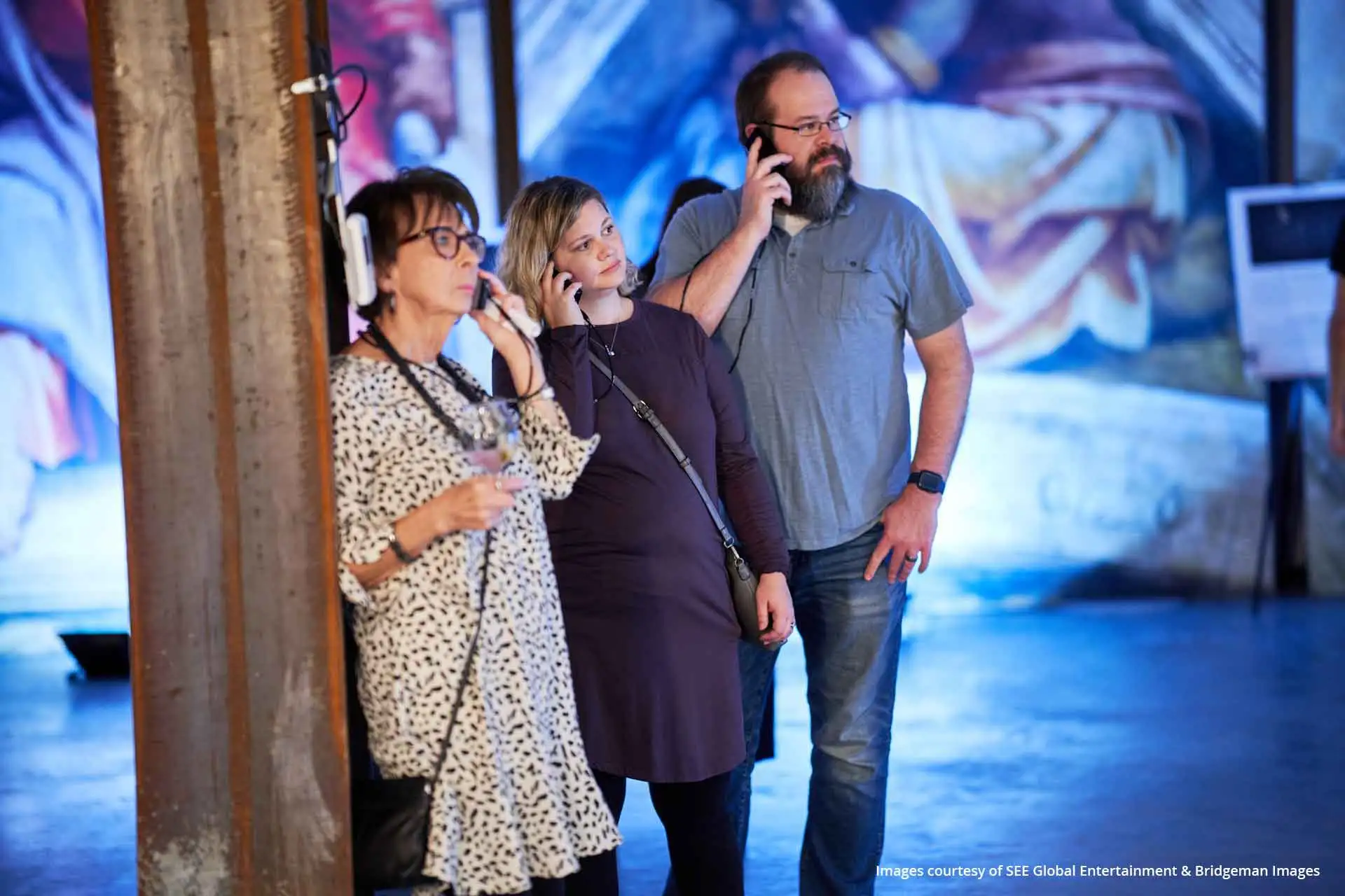 Trois personnes écoutant les Podcatchers Guide-ID lors de l’exposition consacrée à la chapelle Sixtine.