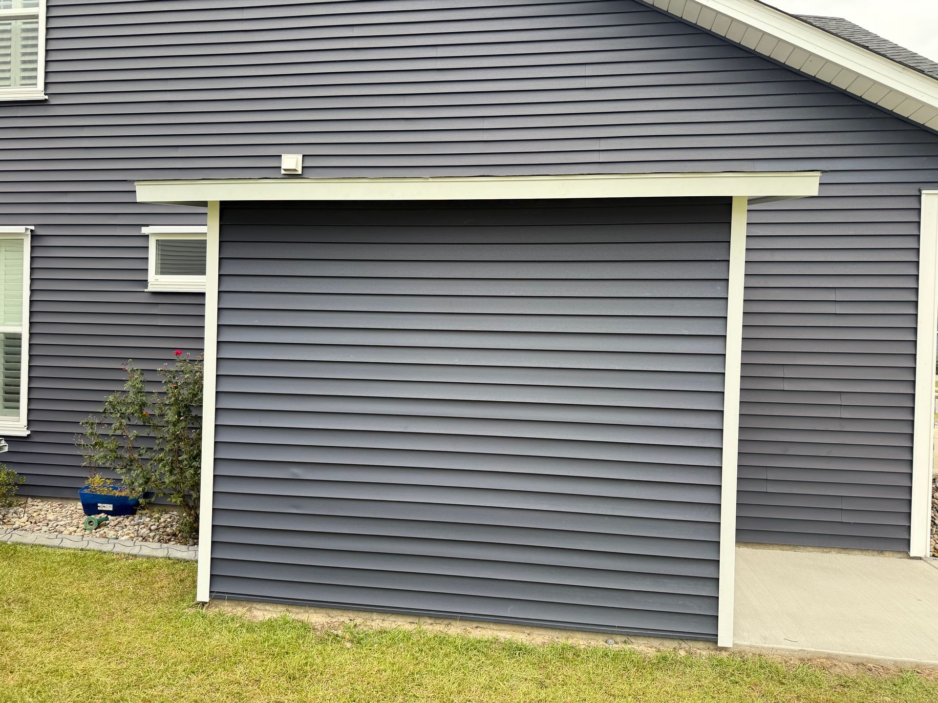 Gray house siding with a dark gray covered entry; white trim and a small lawn.