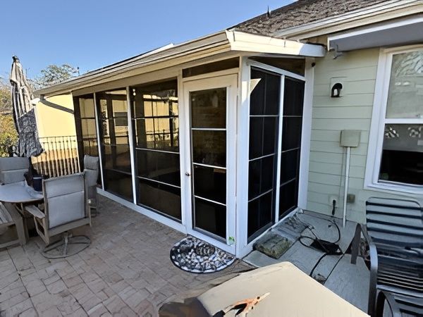 Screened-in porch attached to a house with an outdoor patio area.