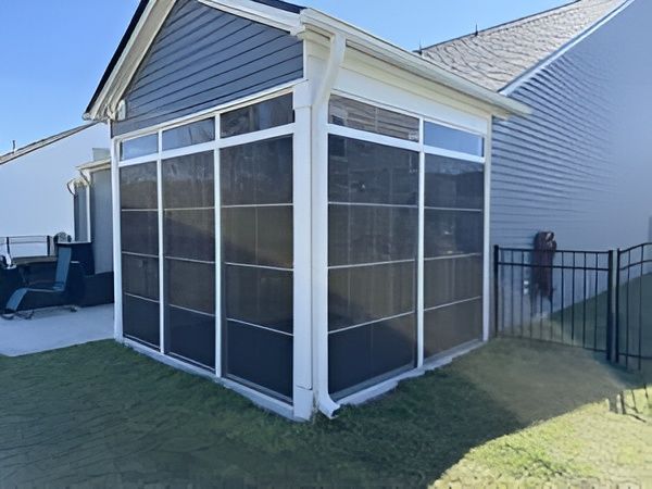 Screened-in porch attached to a house with dark gray siding, white trim, and a black mesh.