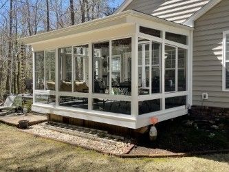 Sunroom addition with white frames and large windows on the side of a house.