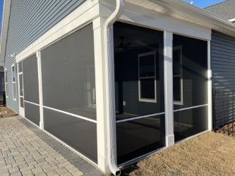 Screened-in porch with dark screens, white trim, and a brick patio. Blue siding on the house.