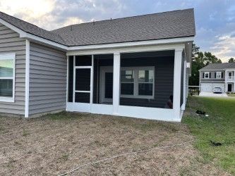 Screened porch attached to a house with gray siding. White trim, door, and a gray roof.