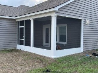Screened porch attached to a gray house, white trim, with door and window visible.